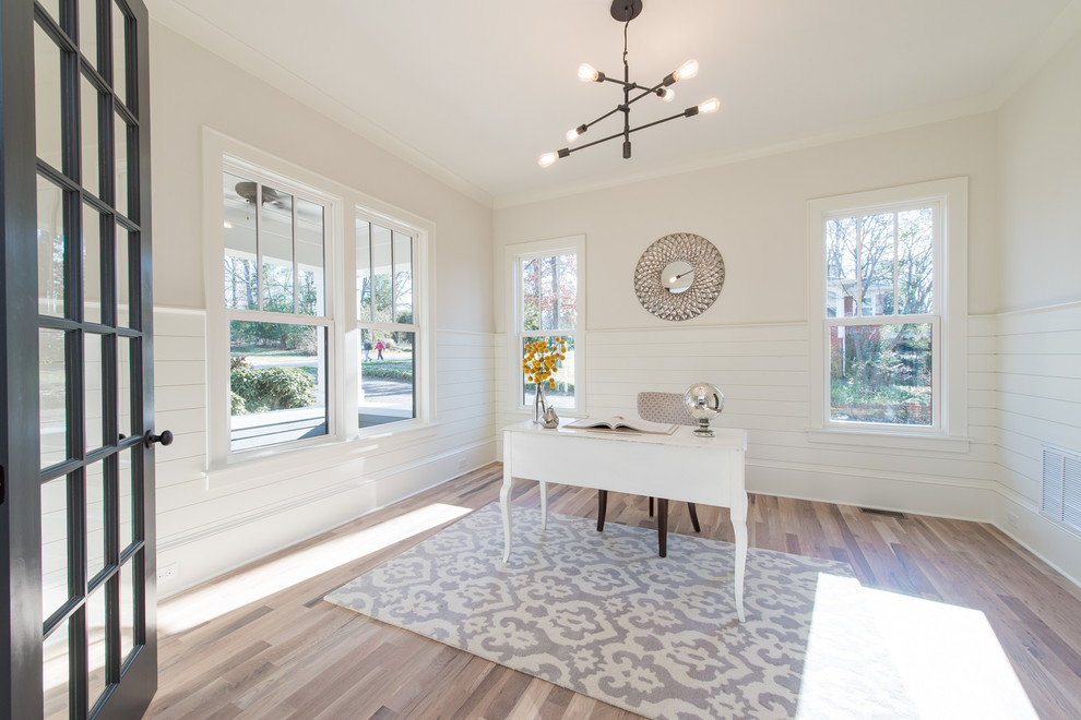 Ejemplo de despacho de estilo americano de tamaño medio con paredes blancas, suelo de madera clara, escritorio independiente y suelo beige
