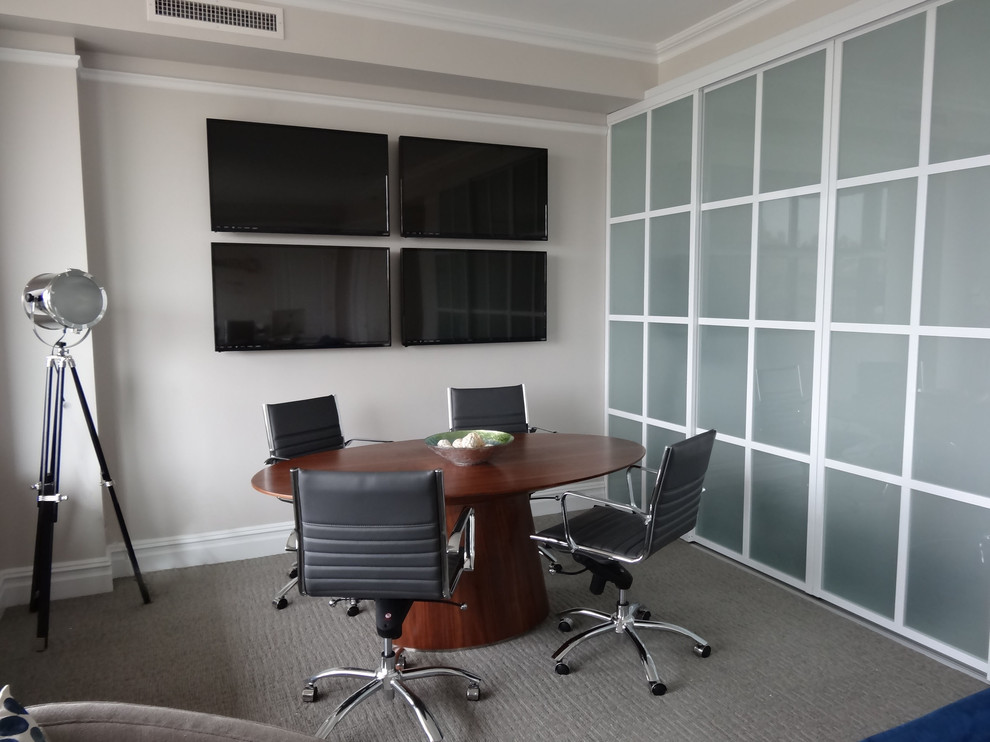 Modern inredning av ett stort arbetsrum, med grå väggar, heltäckningsmatta och ett fristående skrivbord