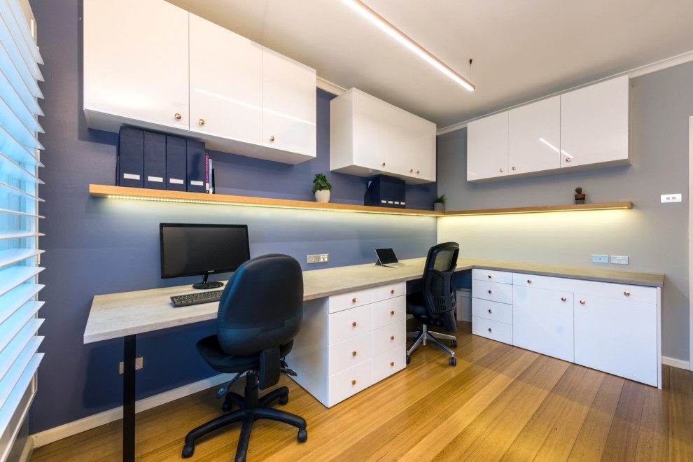 На фото: кабинет среднего размера в стиле модернизм с серыми стенами, полом из ламината и отдельно стоящим рабочим столом с