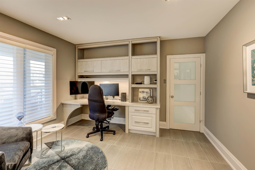 Large contemporary study in Toronto with beige walls, laminate floors, no fireplace, a built-in desk and beige floors.