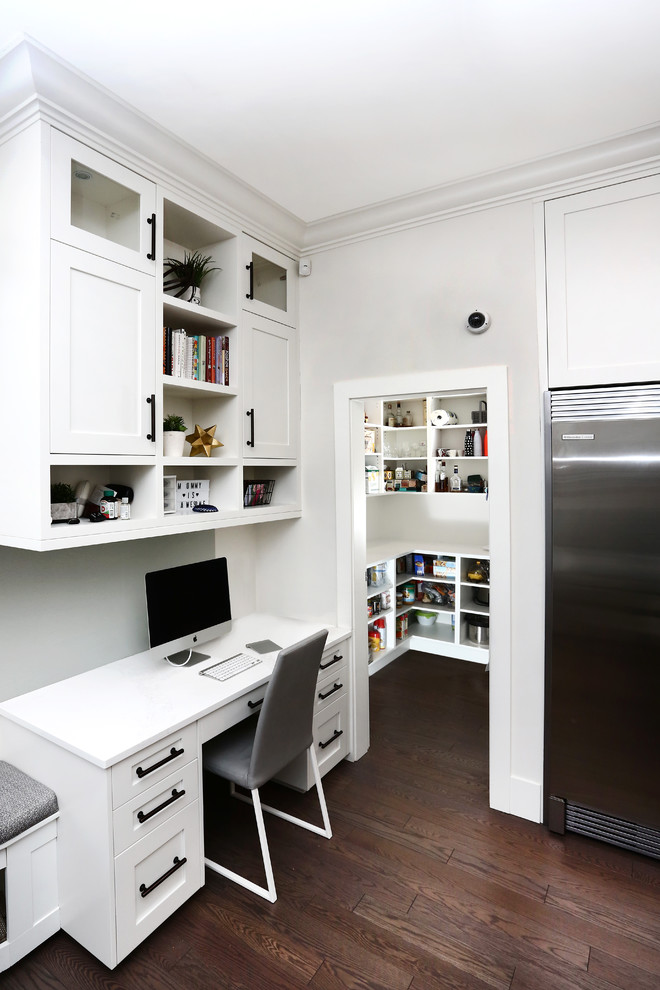 Exempel på ett mycket stort amerikanskt hemmastudio, med vita väggar, mörkt trägolv, ett inbyggt skrivbord och brunt golv