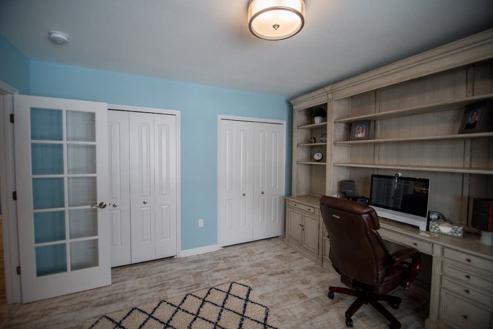 Aménagement d'un bureau campagne de taille moyenne avec un bureau intégré, un mur bleu, un sol en vinyl, aucune cheminée et un sol beige.
