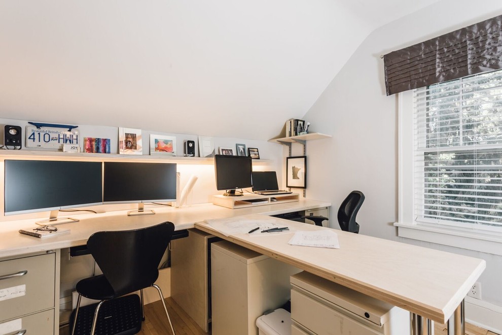 Ejemplo de despacho actual de tamaño medio sin chimenea con paredes blancas, suelo de madera clara y escritorio empotrado