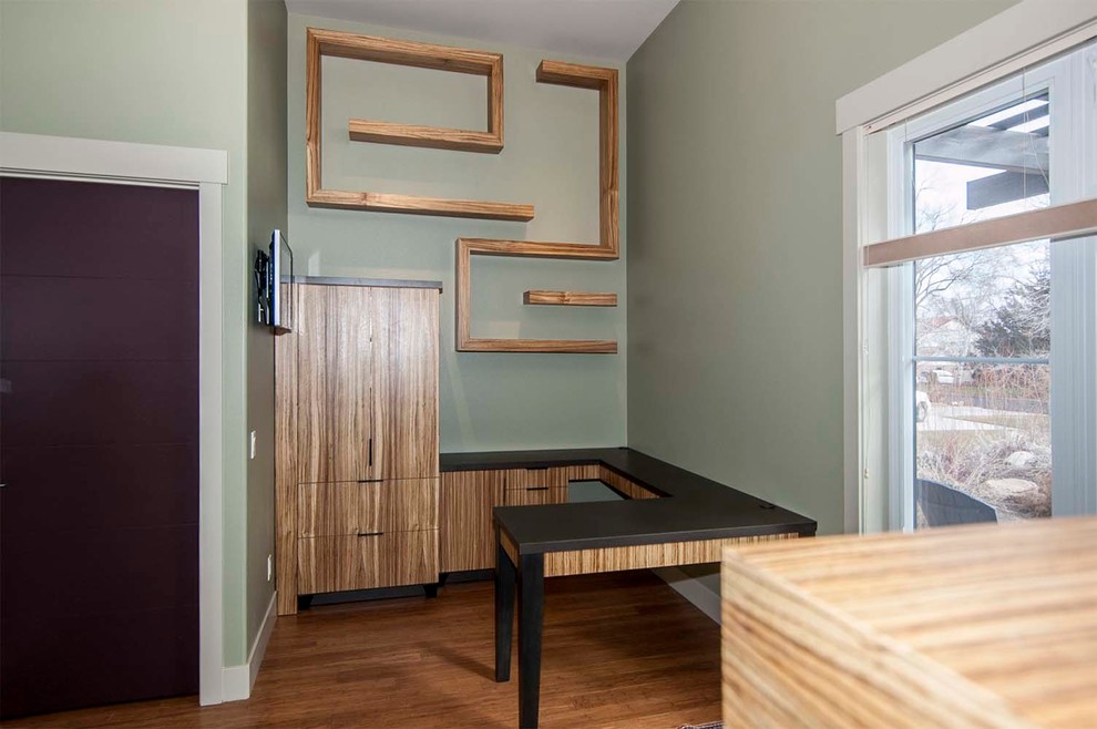 Ejemplo de despacho actual de tamaño medio con paredes verdes, suelo de madera oscura y escritorio empotrado