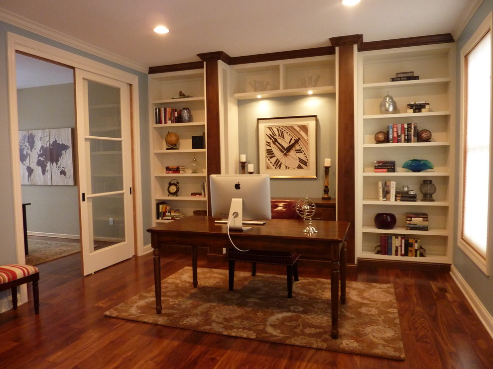 Imagen de despacho de estilo americano de tamaño medio con paredes azules, suelo de madera en tonos medios y escritorio independiente