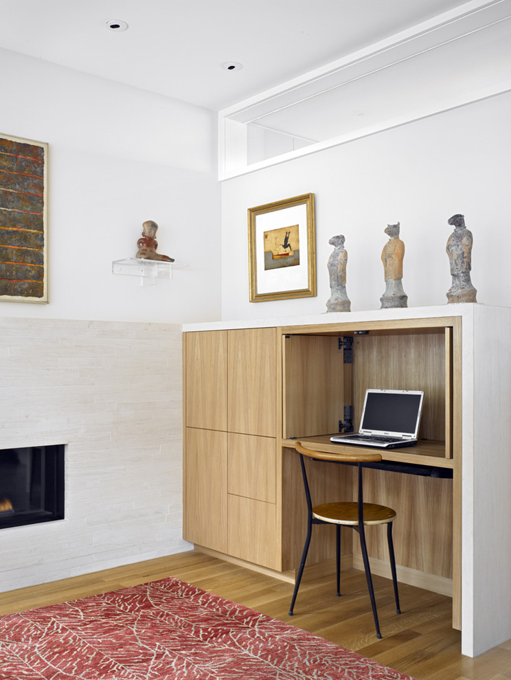 Cette photo montre un bureau moderne de taille moyenne avec un bureau intégré, un mur blanc, une cheminée ribbon et un sol en bois brun.