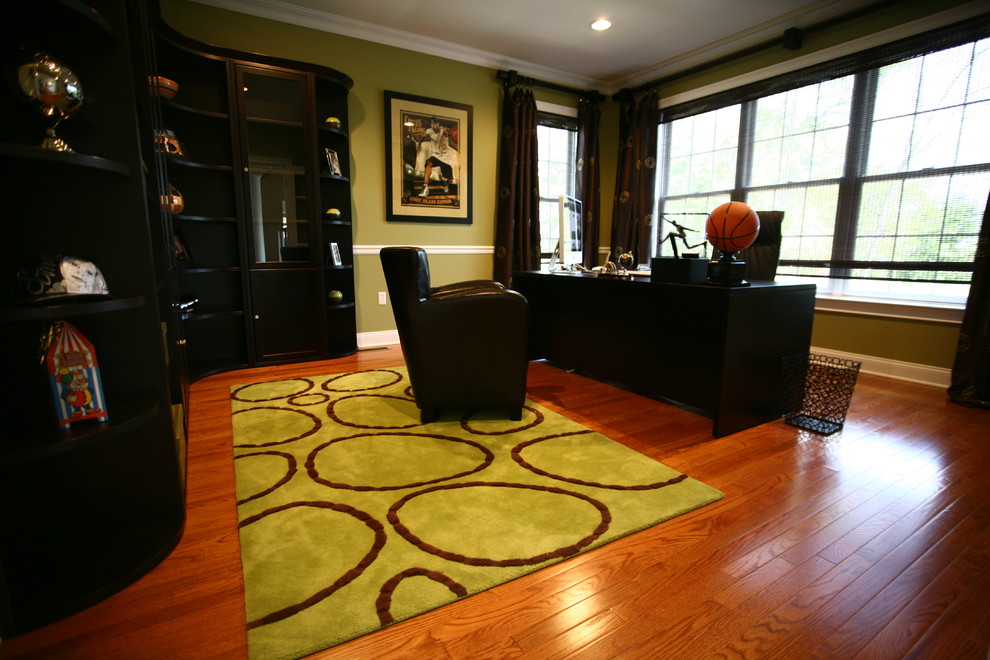 Modelo de despacho clásico renovado de tamaño medio sin chimenea con paredes verdes, suelo de madera en tonos medios y escritorio independiente