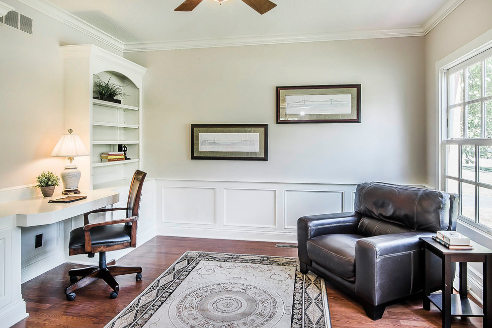 Foto de despacho de tamaño medio con paredes beige, suelo de madera en tonos medios y escritorio empotrado