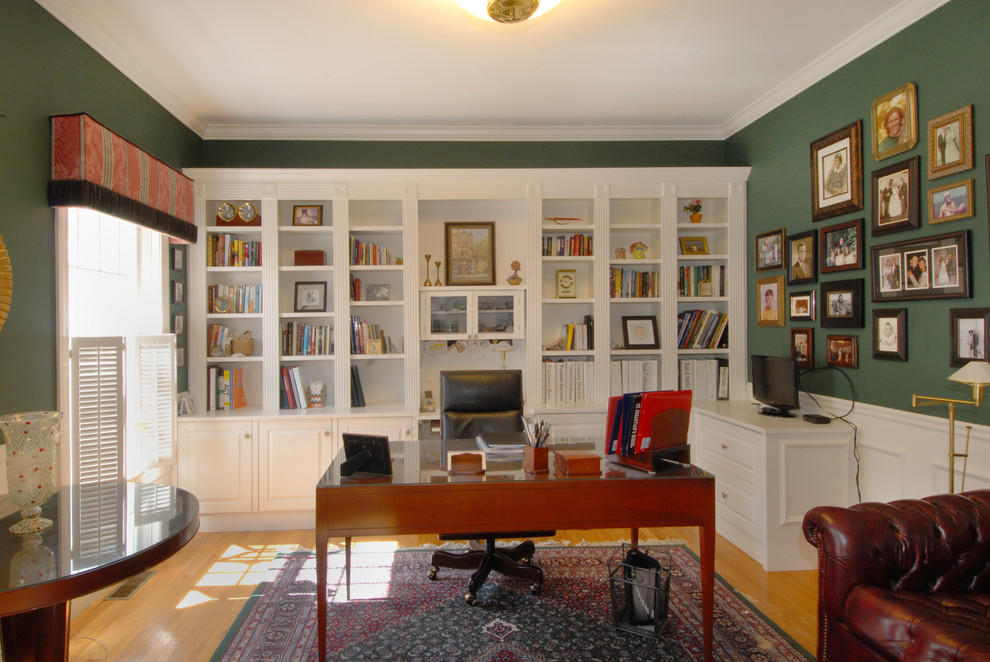 Klassisk inredning av ett stort arbetsrum, med gröna väggar, ljust trägolv och ett fristående skrivbord