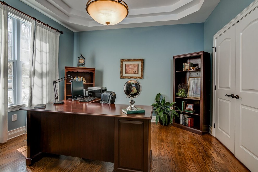 Foto di un ufficio chic con pareti blu, pavimento in legno massello medio, scrivania autoportante e pavimento marrone
