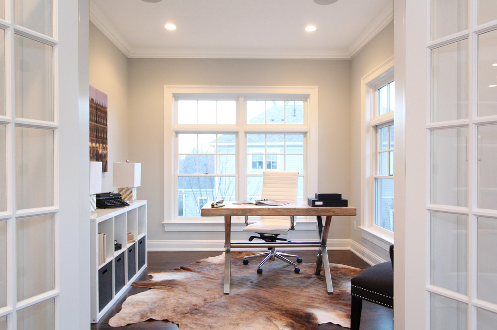 This is an example of a modern study in New York with grey walls, dark hardwood flooring and a freestanding desk.
