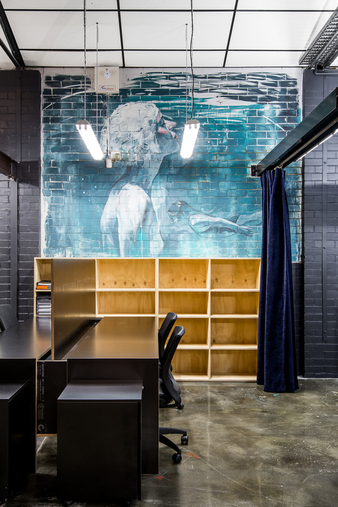 Esempio di uno studio industriale di medie dimensioni con pareti nere, pavimento in cemento e scrivania incassata