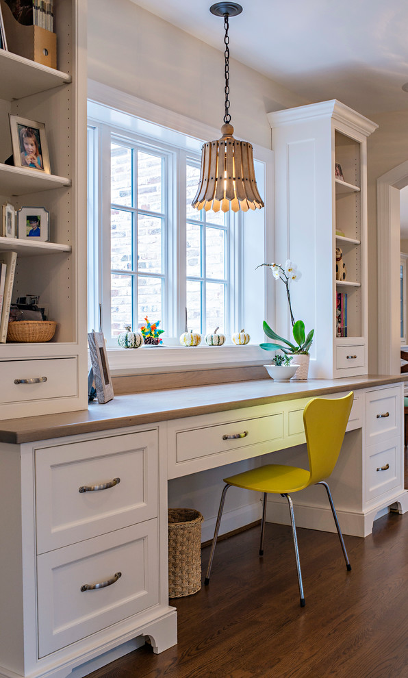 Example of a classic built-in desk medium tone wood floor study room design in Baltimore with white walls