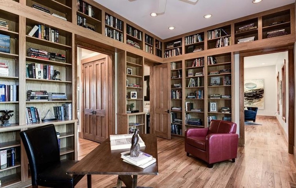 Ejemplo de despacho de estilo americano grande con biblioteca, suelo de madera en tonos medios y escritorio independiente