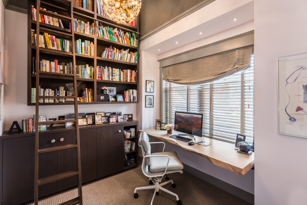 Immagine di un piccolo studio minimal con libreria, pareti bianche, moquette, nessun camino, scrivania incassata e pavimento marrone