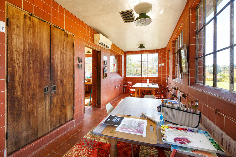 Idéer för ett mellanstort lantligt hobbyrum, med röda väggar, klinkergolv i terrakotta, ett fristående skrivbord och rött golv