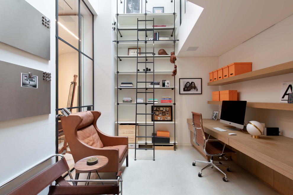 This is an example of a contemporary home office in London with white walls, a built-in desk and grey floors.
