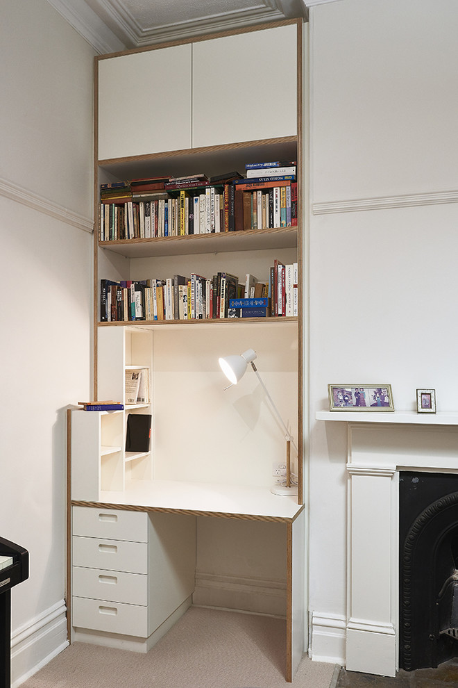 Cette image montre un petit bureau design avec un mur blanc, moquette, une cheminée standard, un manteau de cheminée en métal et un bureau intégré.