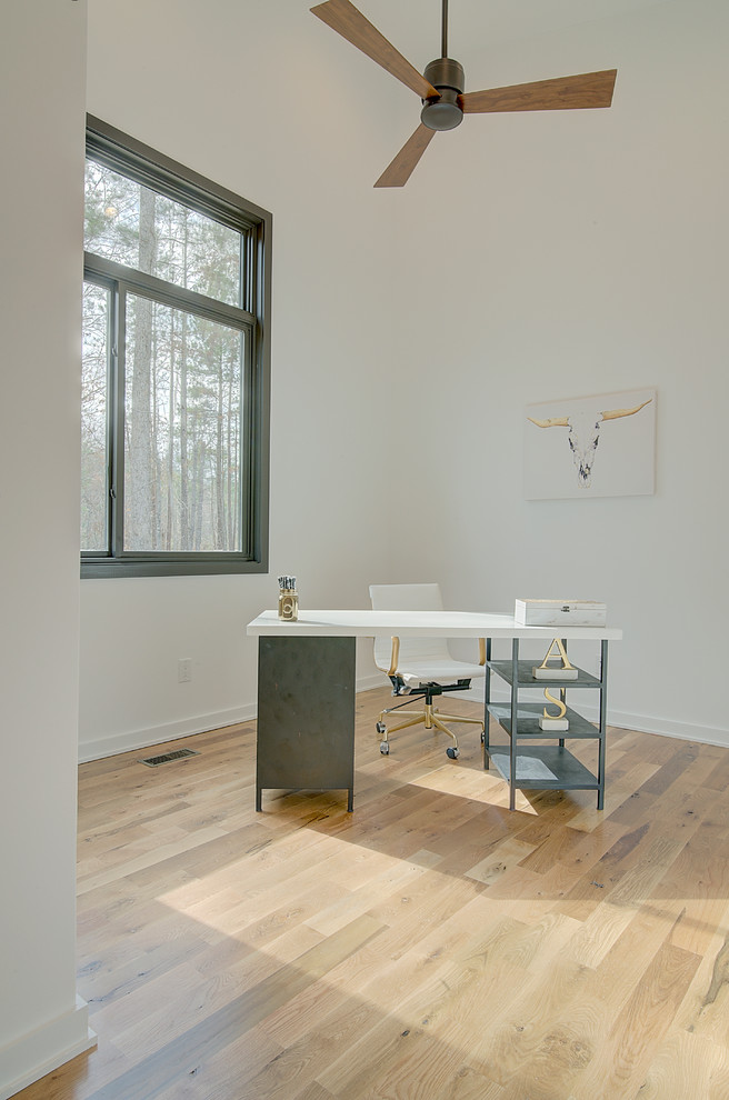 Idee per un piccolo studio moderno con pareti bianche, parquet chiaro e scrivania autoportante