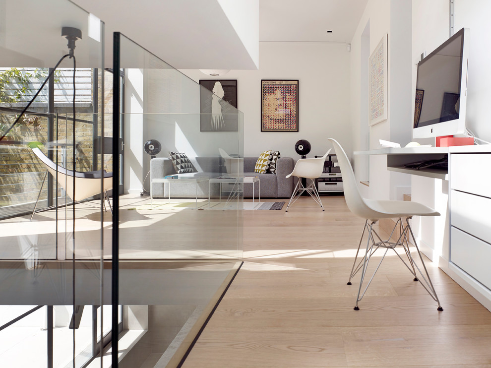 Minimalistisk inredning av ett arbetsrum, med vita väggar, ljust trägolv, ett inbyggt skrivbord och beiget golv