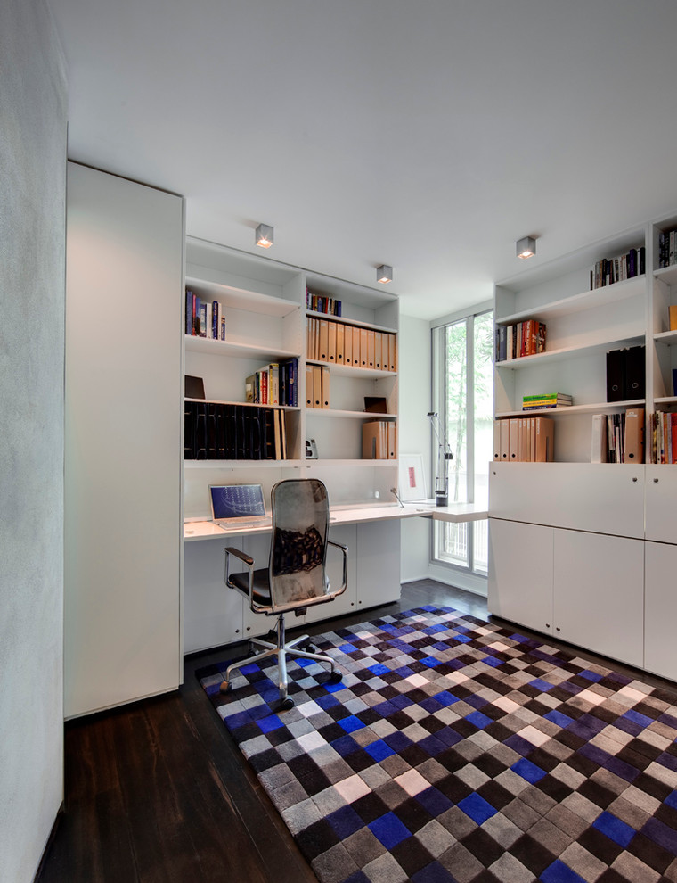 Inspiration för ett funkis hemmabibliotek, med vita väggar, mörkt trägolv och ett inbyggt skrivbord