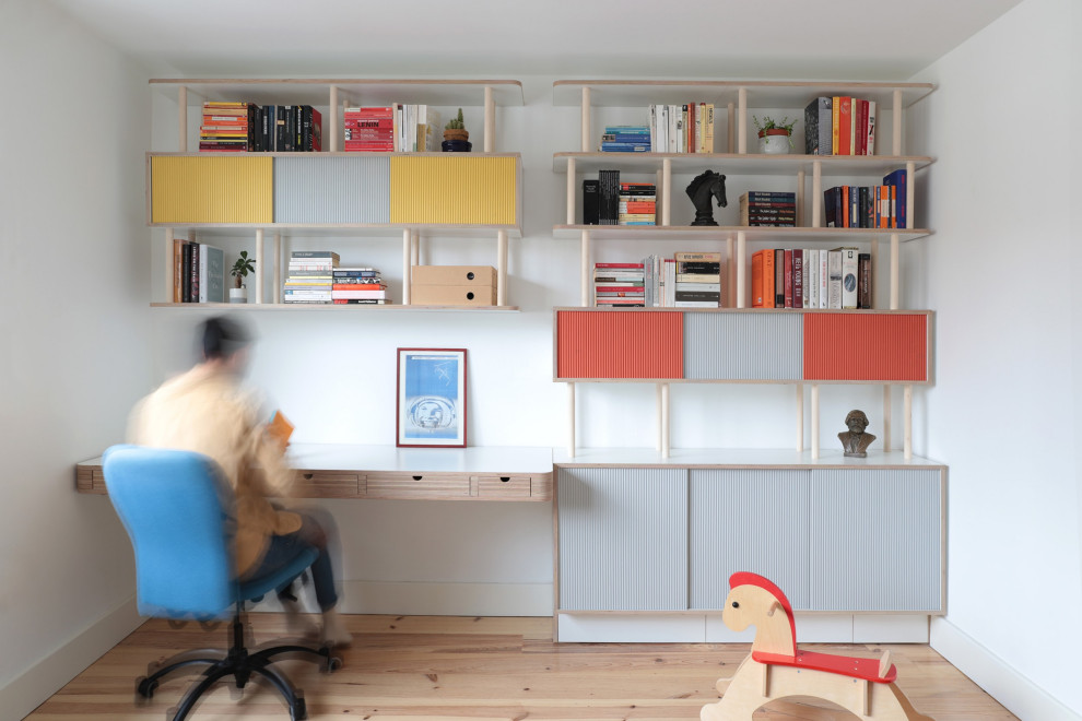Diseño de despacho nórdico sin chimenea con biblioteca, paredes blancas, suelo de madera clara y escritorio empotrado