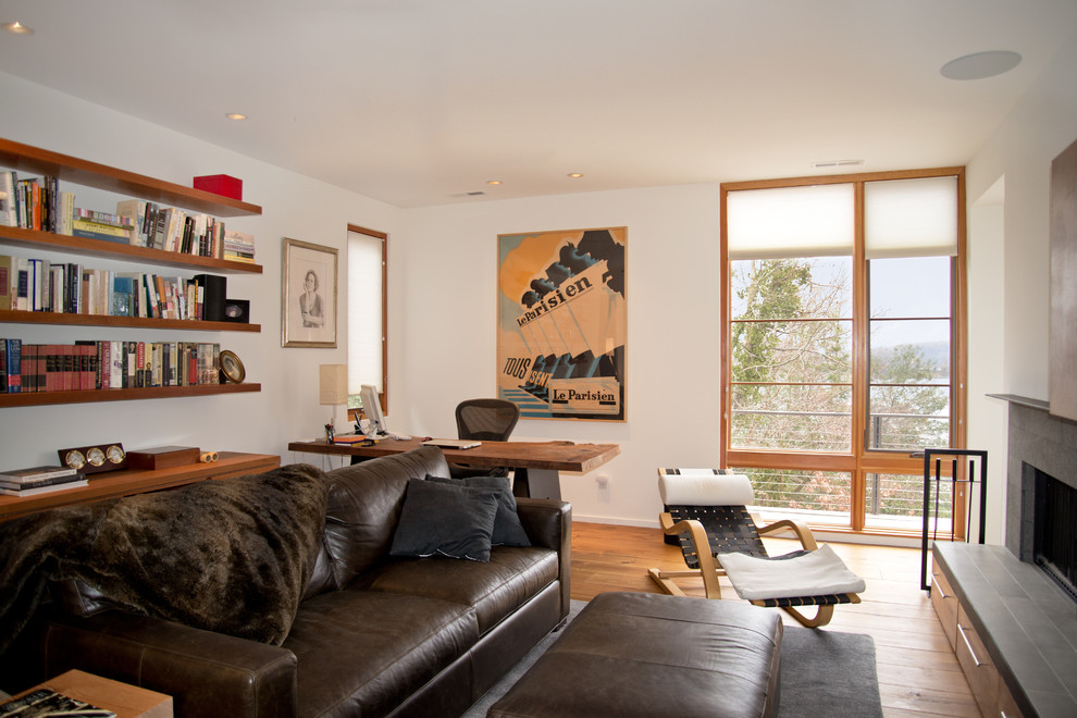 Imagen de despacho moderno de tamaño medio con paredes blancas, suelo de madera clara, todas las chimeneas, marco de chimenea de piedra y escritorio independiente