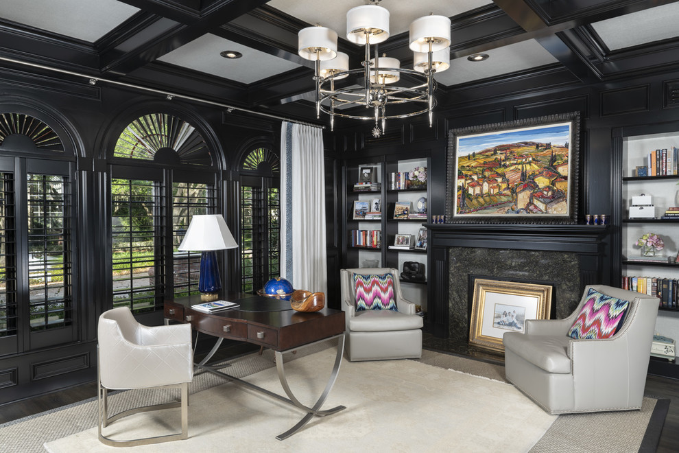 Example of a transitional freestanding desk dark wood floor and brown floor home office design in Tampa with black walls and a standard fireplace