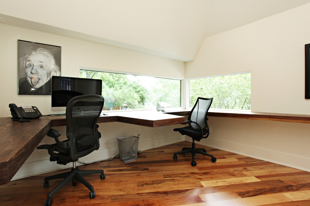 Réalisation d'un grand bureau design avec un bureau intégré, un mur blanc, un sol en bois brun et aucune cheminée.