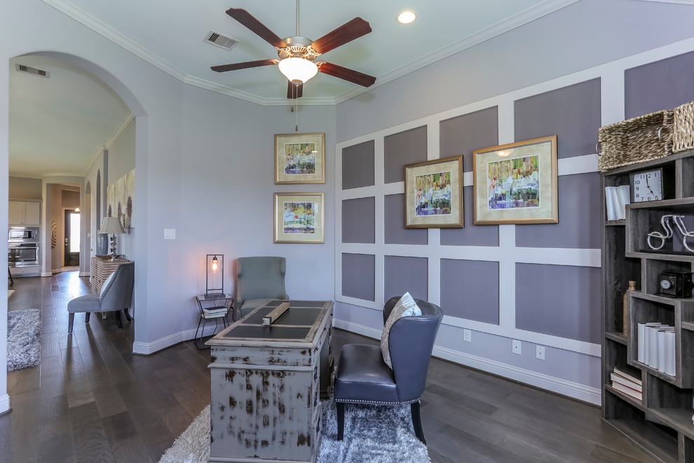 Large freestanding desk dark wood floor and brown floor study room photo in Houston with purple walls