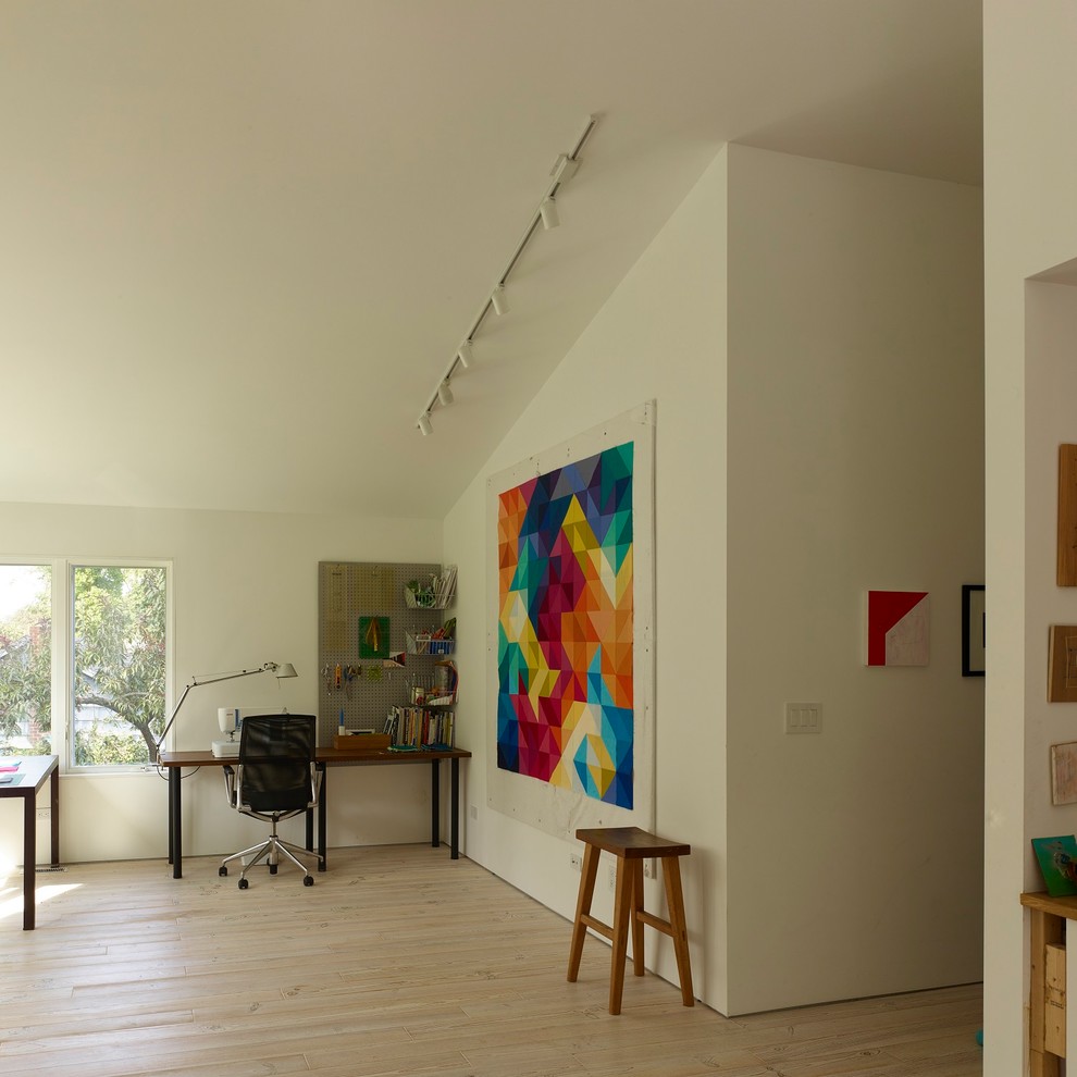 Landhaus Arbeitszimmer mit Arbeitsplatz, beiger Wandfarbe, hellem Holzboden, freistehendem Schreibtisch und beigem Boden in New York