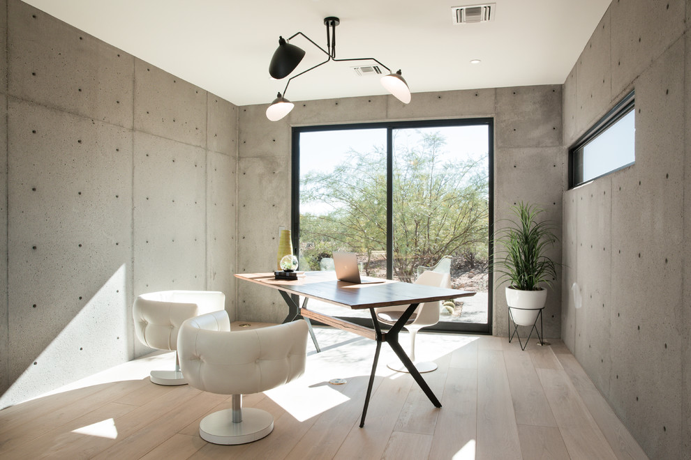 Mittelgroßes Modernes Arbeitszimmer mit Arbeitsplatz, hellem Holzboden, Tunnelkamin, Kaminumrandung aus Beton und freistehendem Schreibtisch in Phoenix