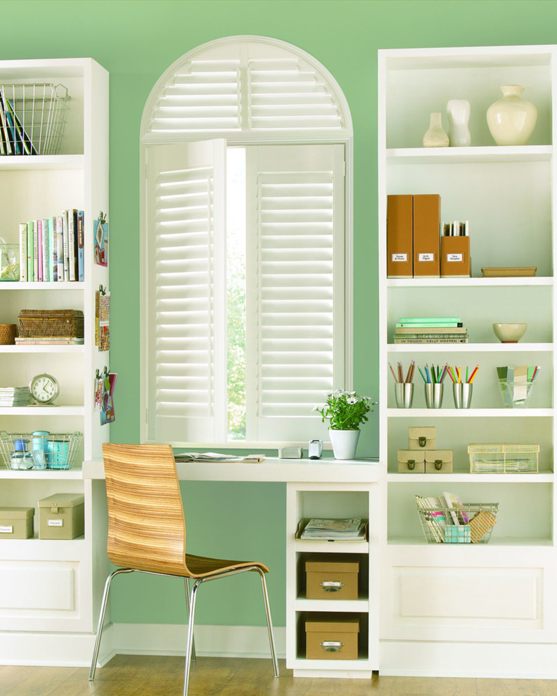 他の地域にある小さなトランジショナルスタイルのおしゃれなホームオフィス・書斎 (緑の壁、淡色無垢フローリング、造り付け机) の写真