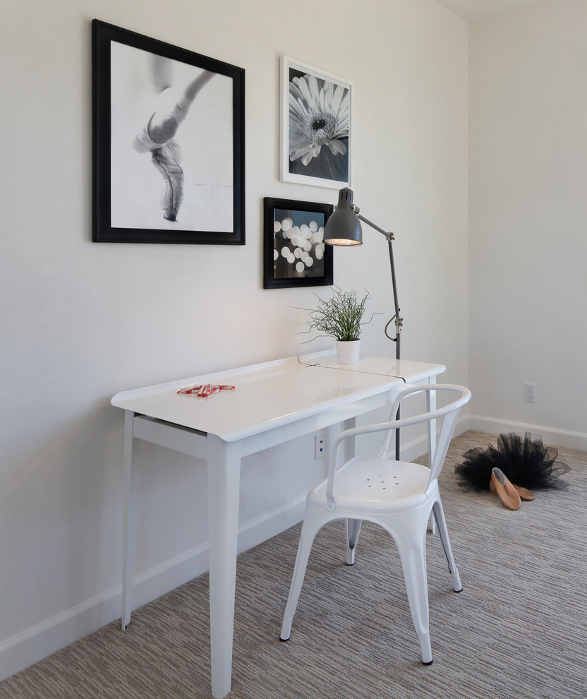 This is an example of a small contemporary home office in Orange County with white walls, carpet and a freestanding desk.