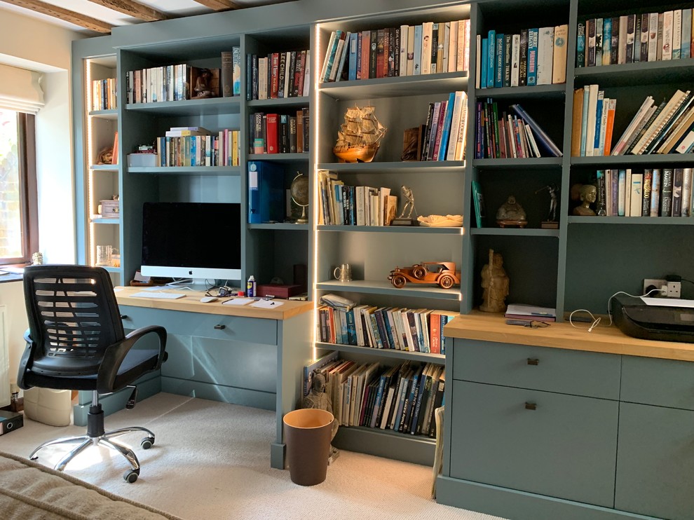 Idéer för ett stort modernt hemmabibliotek, med beige väggar, heltäckningsmatta, en hängande öppen spis, en spiselkrans i tegelsten, ett inbyggt skrivbord och beiget golv