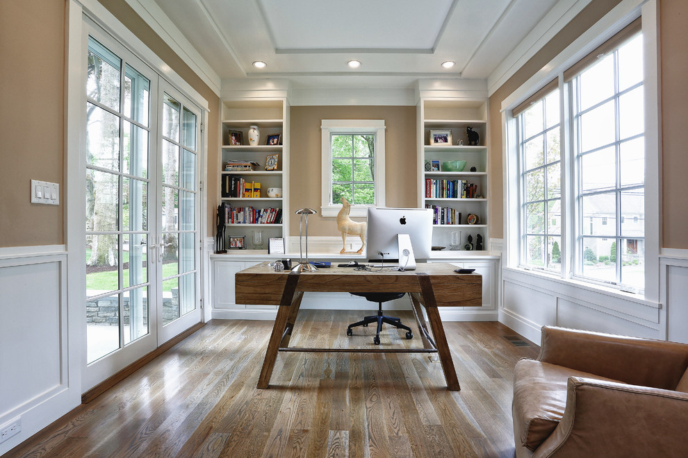 Esempio di un ufficio tradizionale di medie dimensioni con pareti beige, pavimento in legno massello medio, scrivania autoportante e pavimento marrone