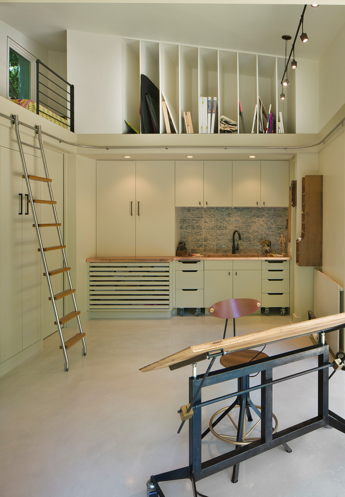 Modelo de estudio contemporáneo sin chimenea con paredes blancas, suelo de cemento y escritorio independiente