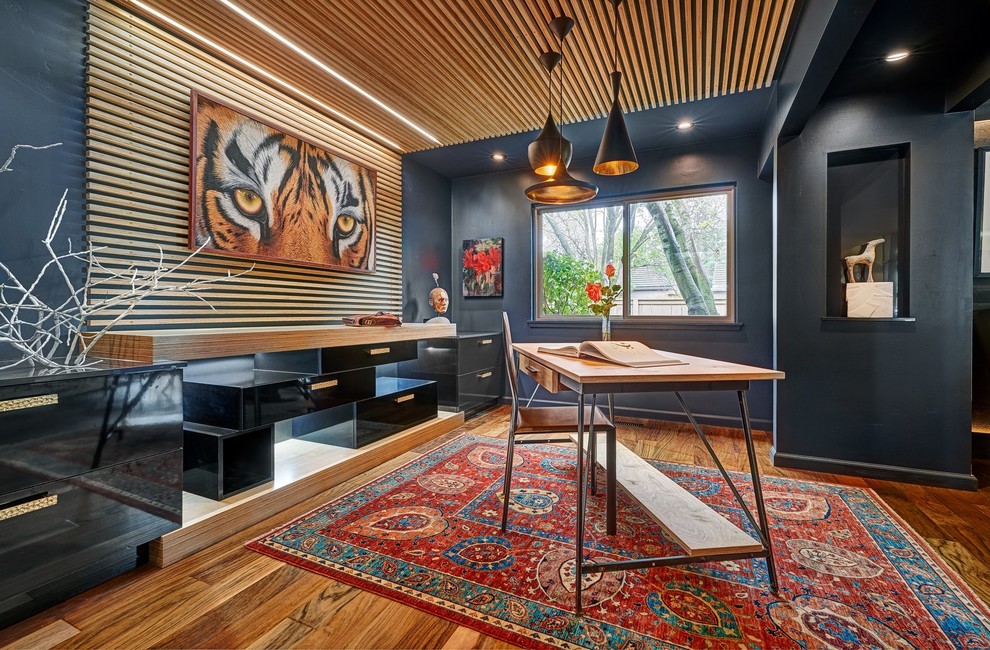 Modern inredning av ett arbetsrum, med blå väggar, mellanmörkt trägolv, ett fristående skrivbord och brunt golv