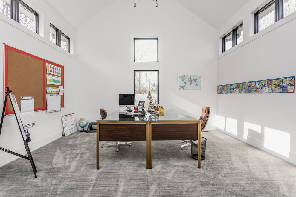На фото: кабинет в современном стиле с белыми стенами, ковровым покрытием, отдельно стоящим рабочим столом и серым полом