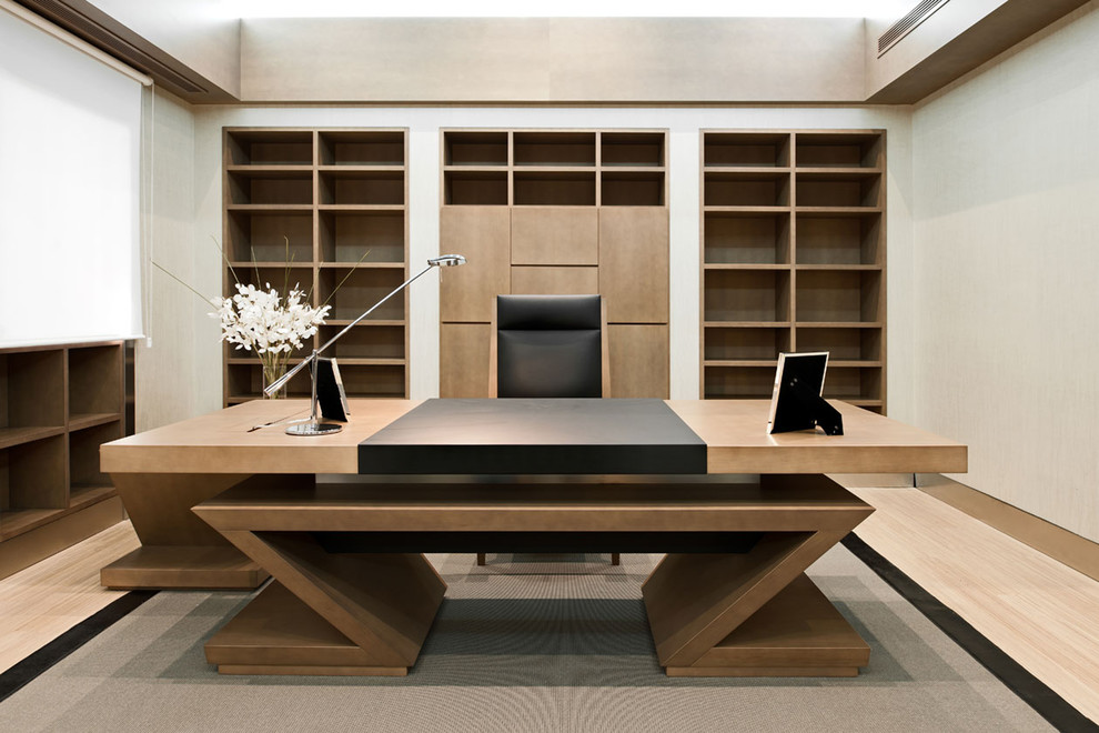 Modelo de despacho tradicional renovado de tamaño medio sin chimenea con paredes grises, suelo de madera clara y escritorio empotrado