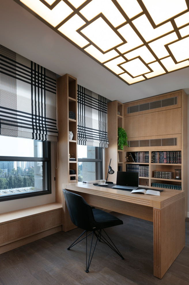 Modelo de despacho contemporáneo de tamaño medio con biblioteca, suelo de madera en tonos medios, escritorio independiente, suelo marrón y paredes beige