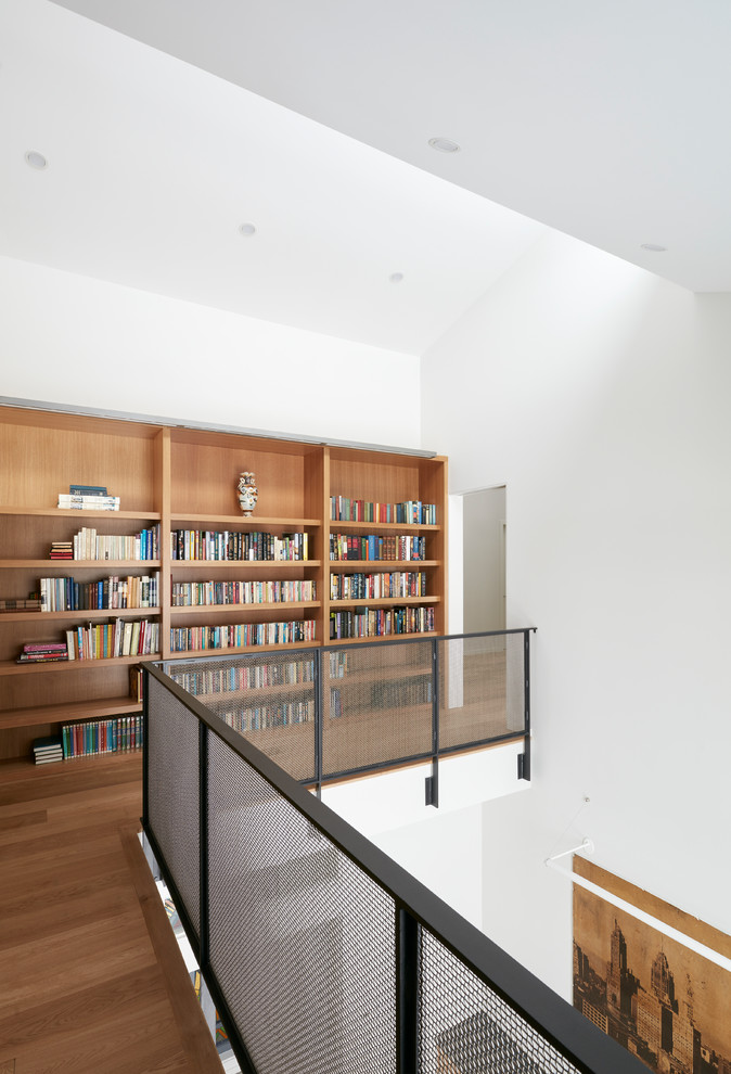 Immagine di un ampio studio moderno con libreria, pareti bianche, pavimento in cemento, nessun camino, scrivania incassata e pavimento grigio