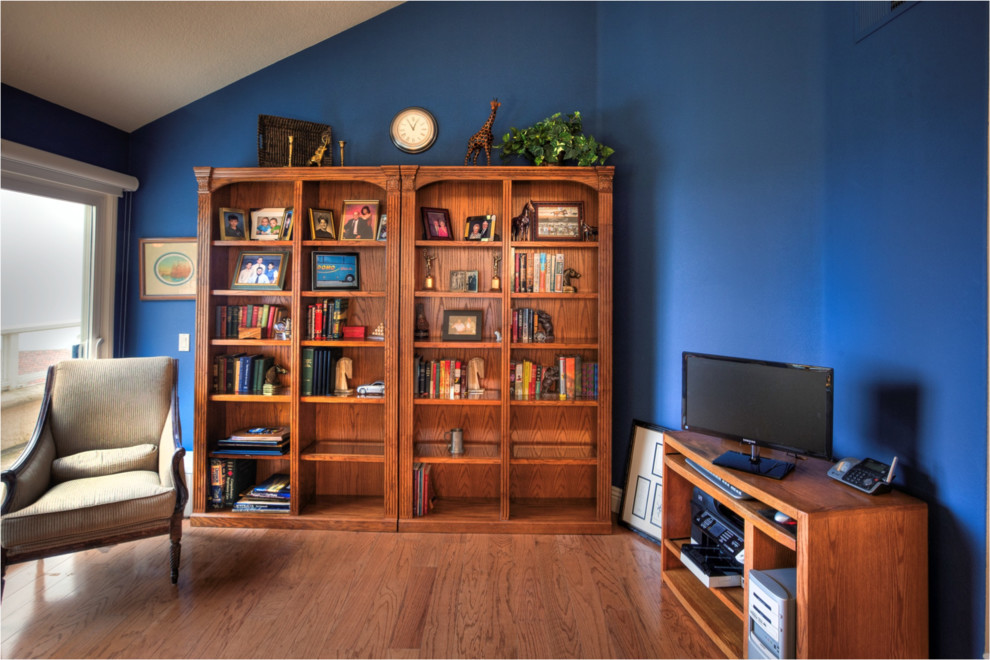 Imagen de despacho mediterráneo grande sin chimenea con paredes azules, suelo de madera en tonos medios y escritorio independiente