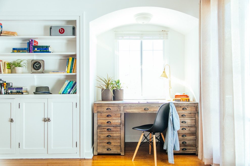 Foto de despacho ecléctico con paredes blancas, suelo de madera en tonos medios y escritorio independiente