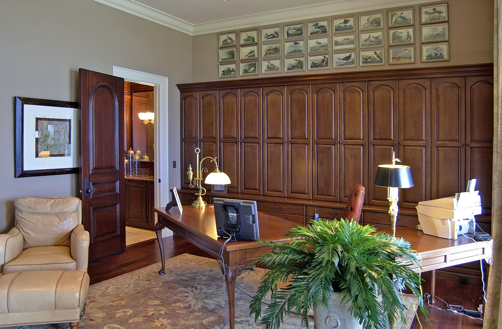 На фото: кабинет среднего размера в средиземноморском стиле с бежевыми стенами, темным паркетным полом, отдельно стоящим рабочим столом и коричневым полом с