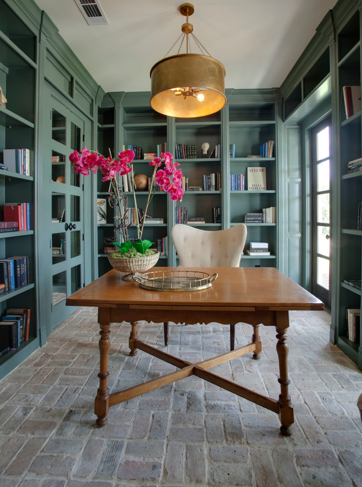 Ejemplo de despacho mediterráneo de tamaño medio con paredes verdes, suelo de ladrillo y escritorio independiente