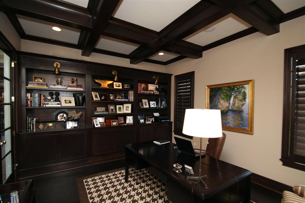 Exempel på ett stort klassiskt arbetsrum, med ett bibliotek, beige väggar, mörkt trägolv, ett fristående skrivbord och brunt golv