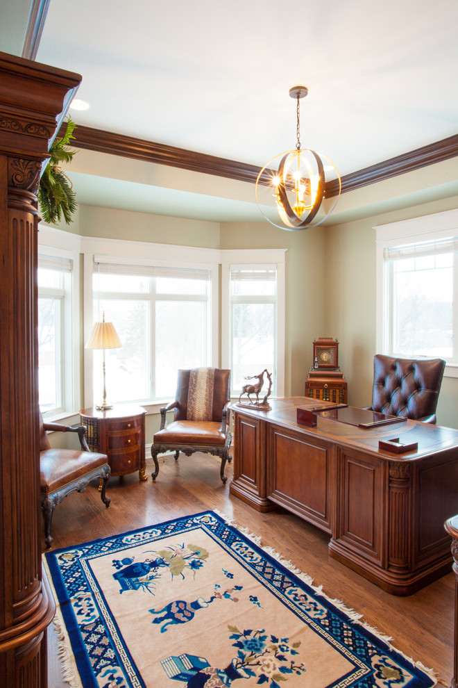 Large classic study in Milwaukee with beige walls, medium hardwood flooring and a freestanding desk.