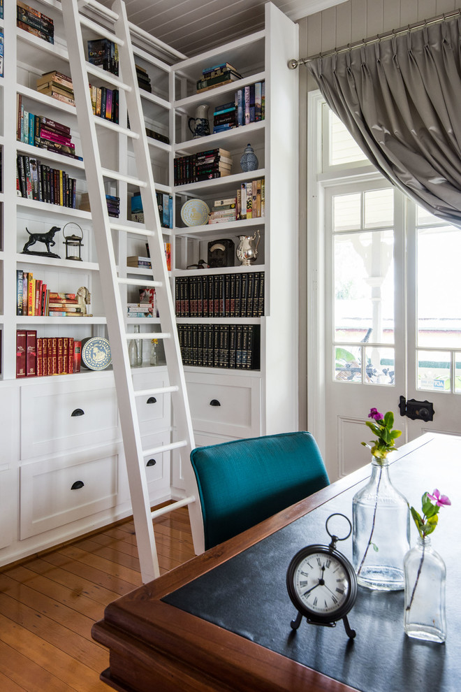 Immagine di uno studio tradizionale con libreria, pavimento in legno massello medio e scrivania autoportante