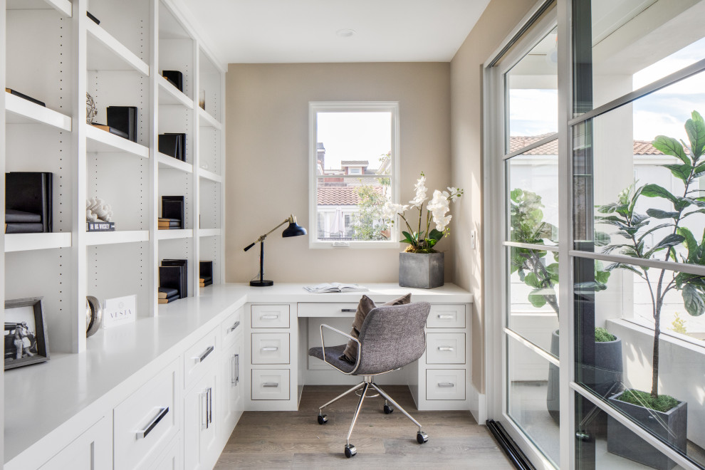 Diseño de despacho tradicional renovado con paredes beige, suelo de madera oscura, escritorio empotrado y suelo marrón